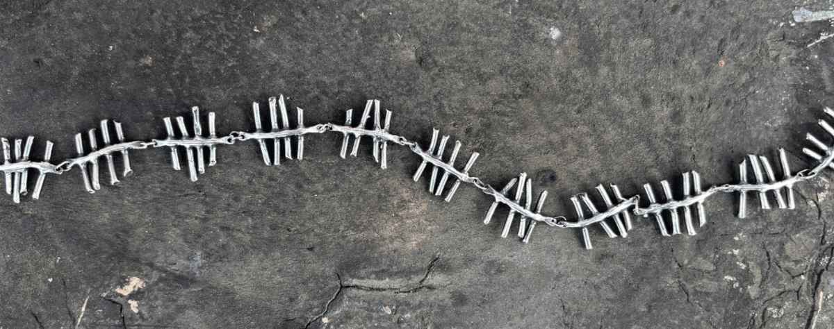 Silver necklace with a geometric pattern on a textured dark surface